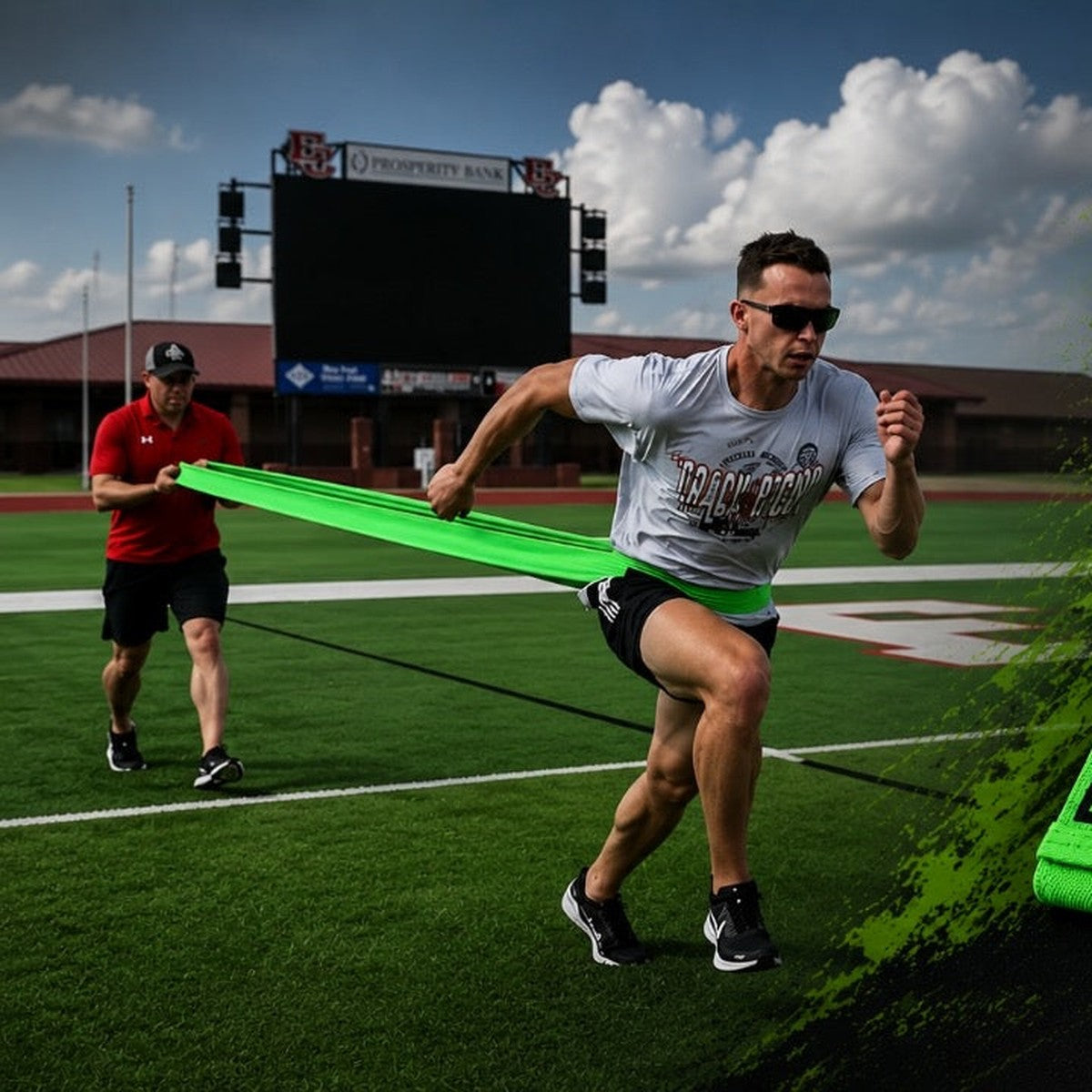 Athlete sprinting on a turf field against a green fabric resistance band held by a partner