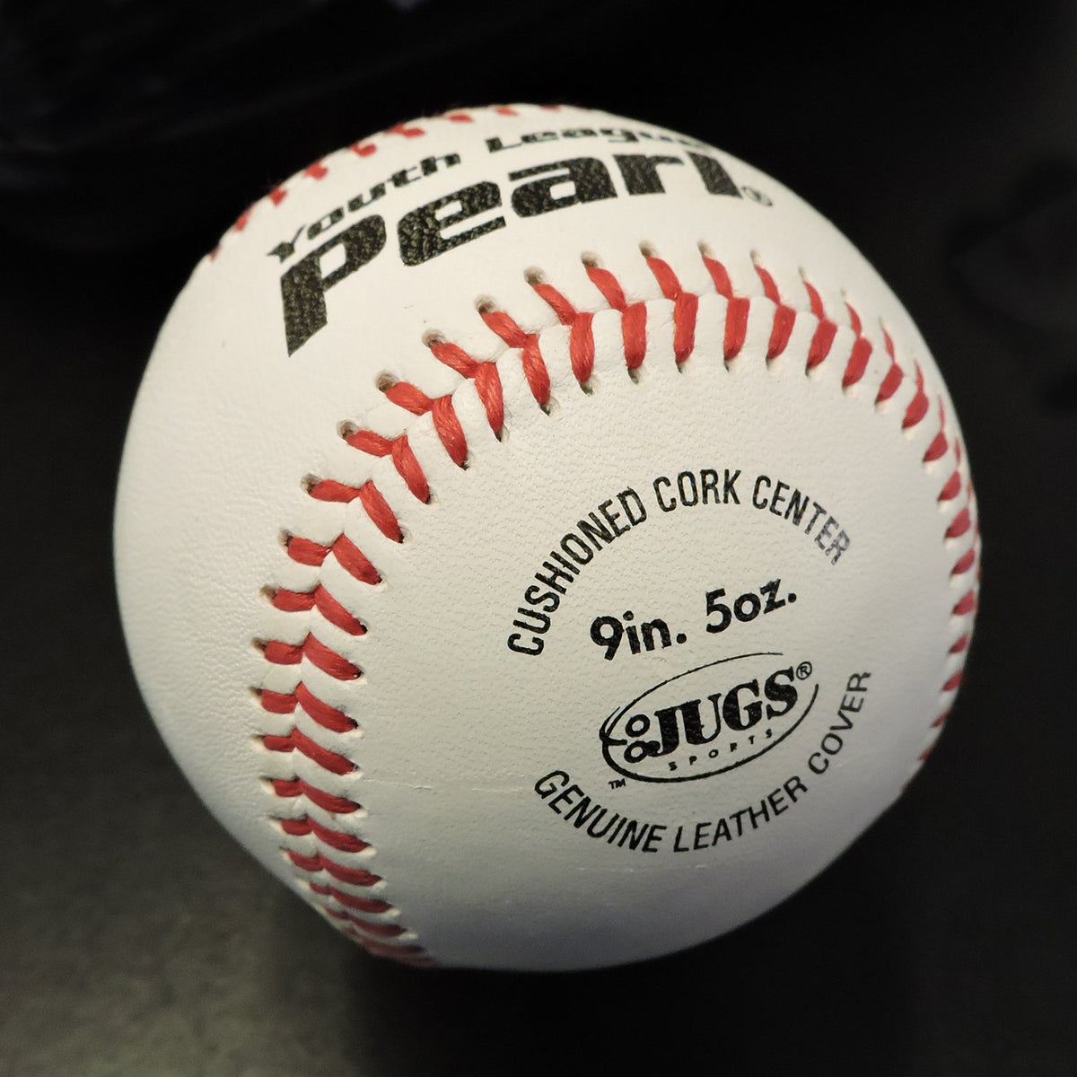 A JUGS Youth League Pearl baseball showing its cushioned cork center and genuine leather cover stamp.