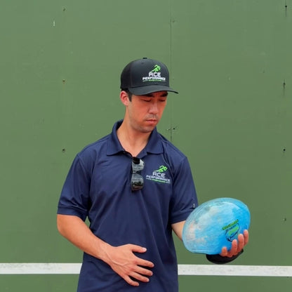 Player with the upper arm at his side rocking the water-filled football back and forth for shoulder stability