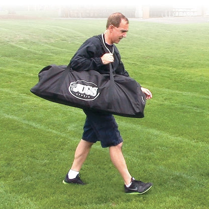 A man carrying the JUGS Backyard Bullpen heavy-duty carry bag across a field.
