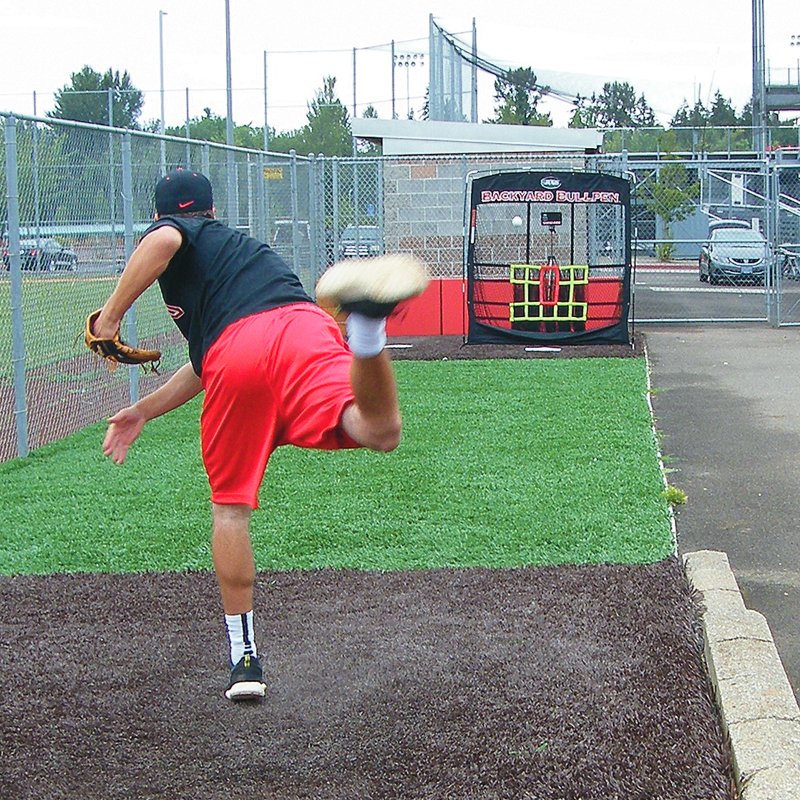 A pitcher throwing toward the JUGS Backyard Bullpen screen in a backyard bullpen area.