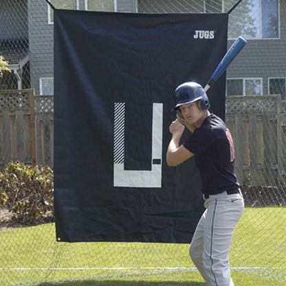A baseball hitter standing in front of the JUGS Backdrop and Pitcher's Trainer hung in a backyard.