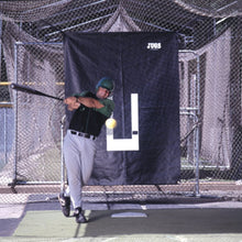 A batter swinging at a ball in a netted batting cage with the black JUGS backdrop with a white strike zone outline hanging behind home plate.