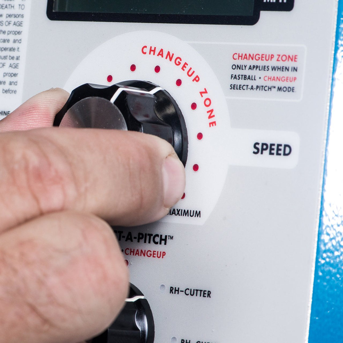 A hand turning the changeup zone dial on the JUGS BP3 baseball control panel, next to the speed control.