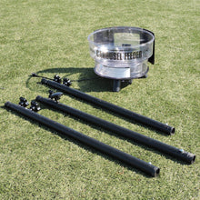 The JUGS Carousel feeder hopper and its three black steel tripod legs laid out on grass before assembly.
