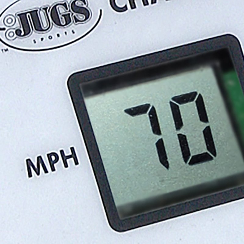 A close-up of a digital display on a JUGS pitching machine control panel reading 70 MPH.