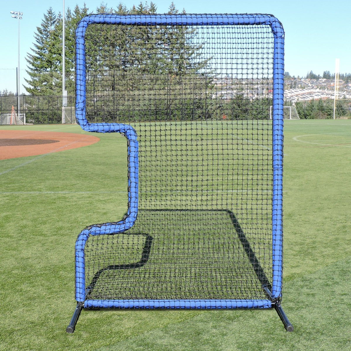 The JUGS Protector Blue Series C-Shaped Softball Screen standing on a softball field.