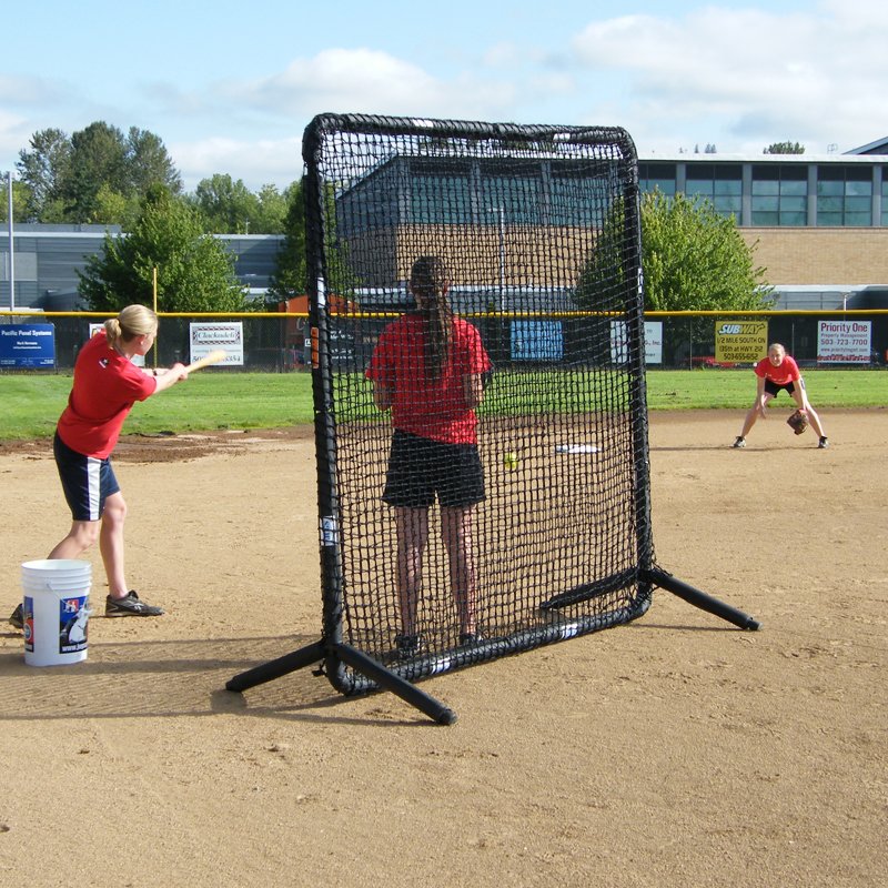 Softball players fielding near the JUGS Protector Series Square Baseman Screen on a dirt infield.