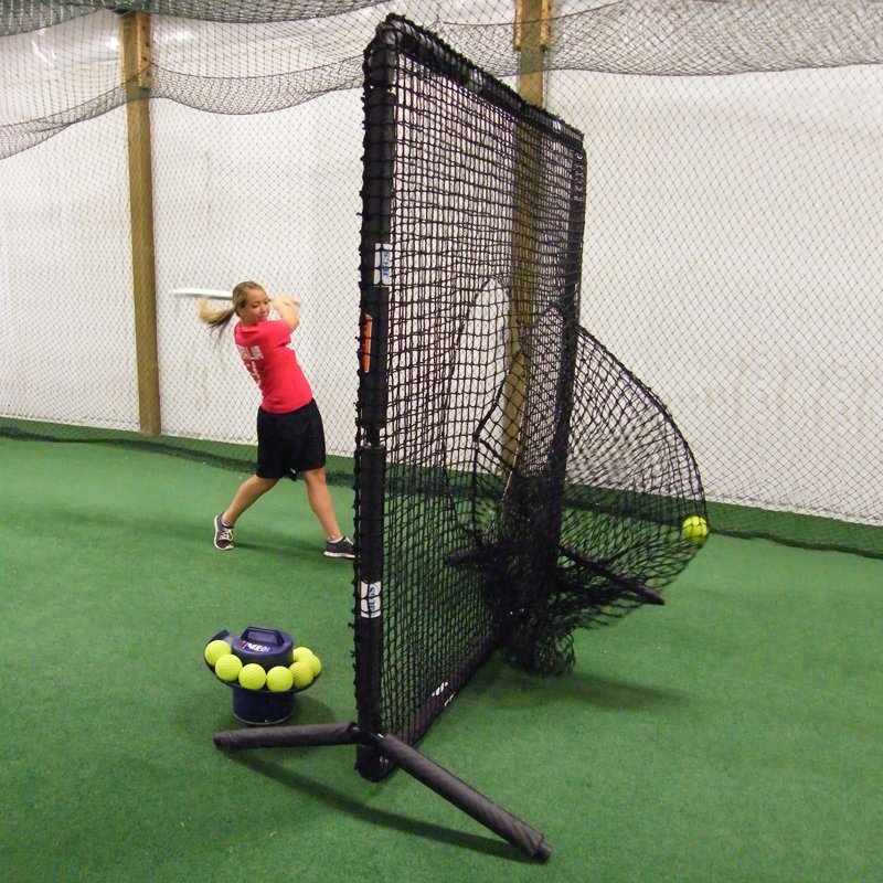A softball player hitting into the sock net of the JUGS Protector Series Square Screen inside an indoor facility.