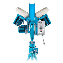 Front view of the light blue JUGS SP3 three-wheel baseball pitching machine with three white wheels, black ball chute and control panel on a tripod base, photographed on a white background.