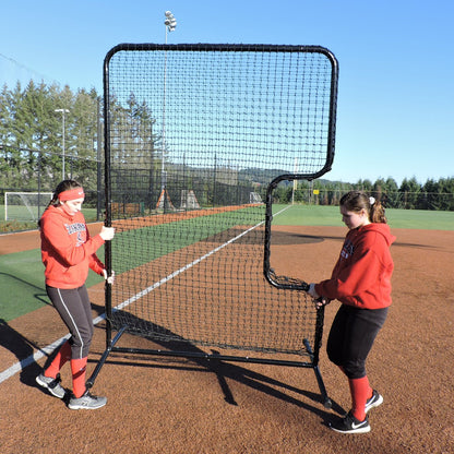 Two softball players carrying the JUGS Standard C-Shaped Softball Screen across the infield.
