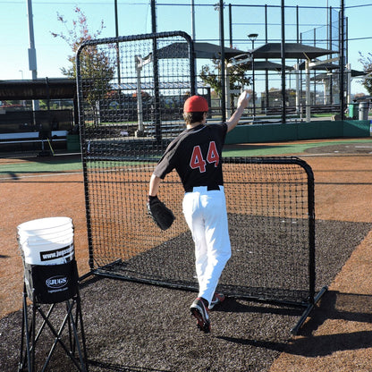 A youth pitcher finishing a throw behind the JUGS Standard L-Shaped Pitchers Screen.
