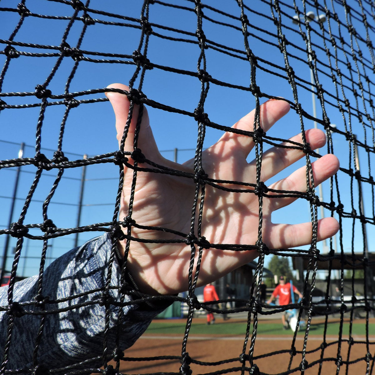 A hand pressed against the netting of a JUGS Standard screen.