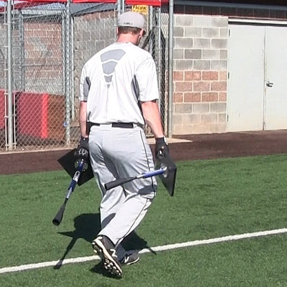 A baseball player carrying the JUGS T tees across a turf field.