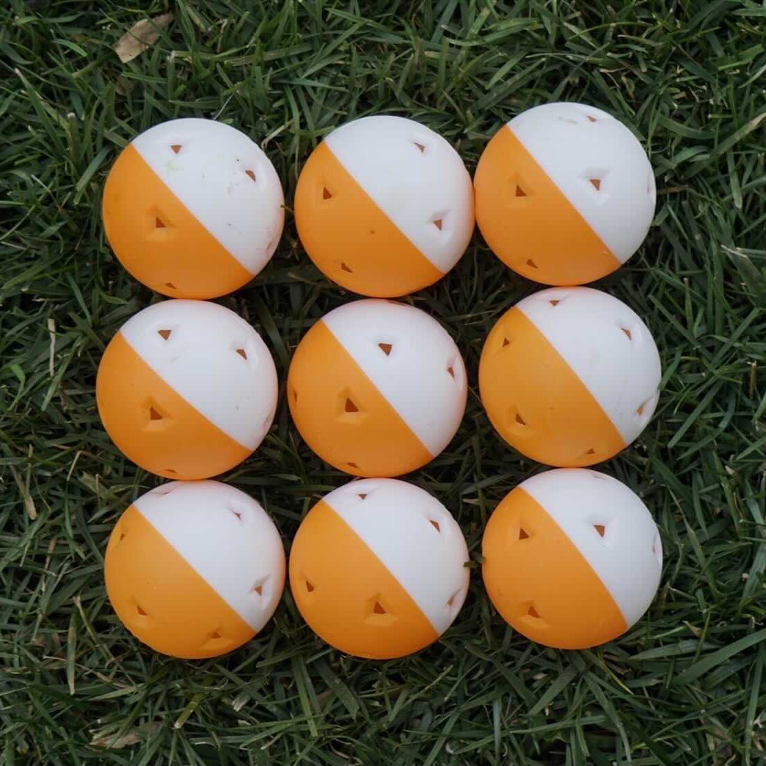 Nine mini training balls arranged in a grid on grass.
