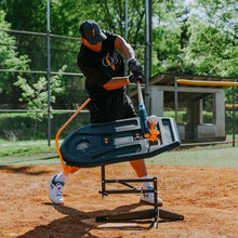 A player takes a swing through the Swing Path Trainer at a field.