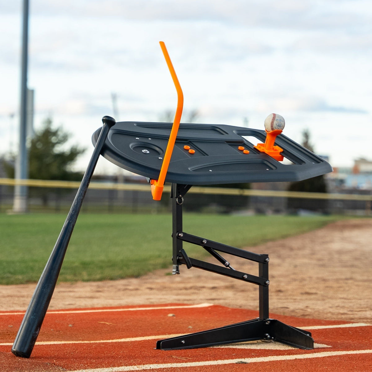 The Swing Path Trainer set up on a baseball field with a bat resting against it.