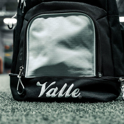 White center panel and embroidered Valle script above the bottom compartment of the black backpack