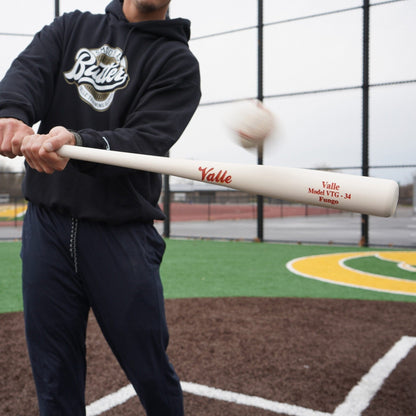 Coach hitting a fungo on a turf infield with the baseball just off the barrel