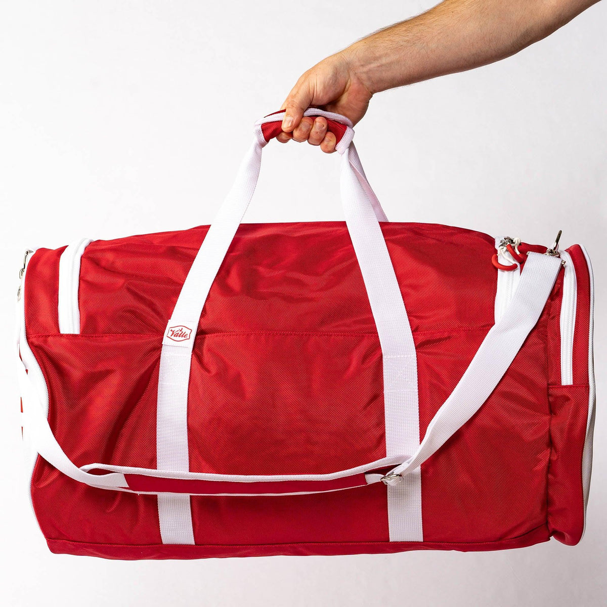 Red Valle Eagle Players Duffle Bag held up by its two white top handles in a studio