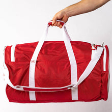 Red Valle Eagle Players Duffle Bag held up by its two white top handles in a studio