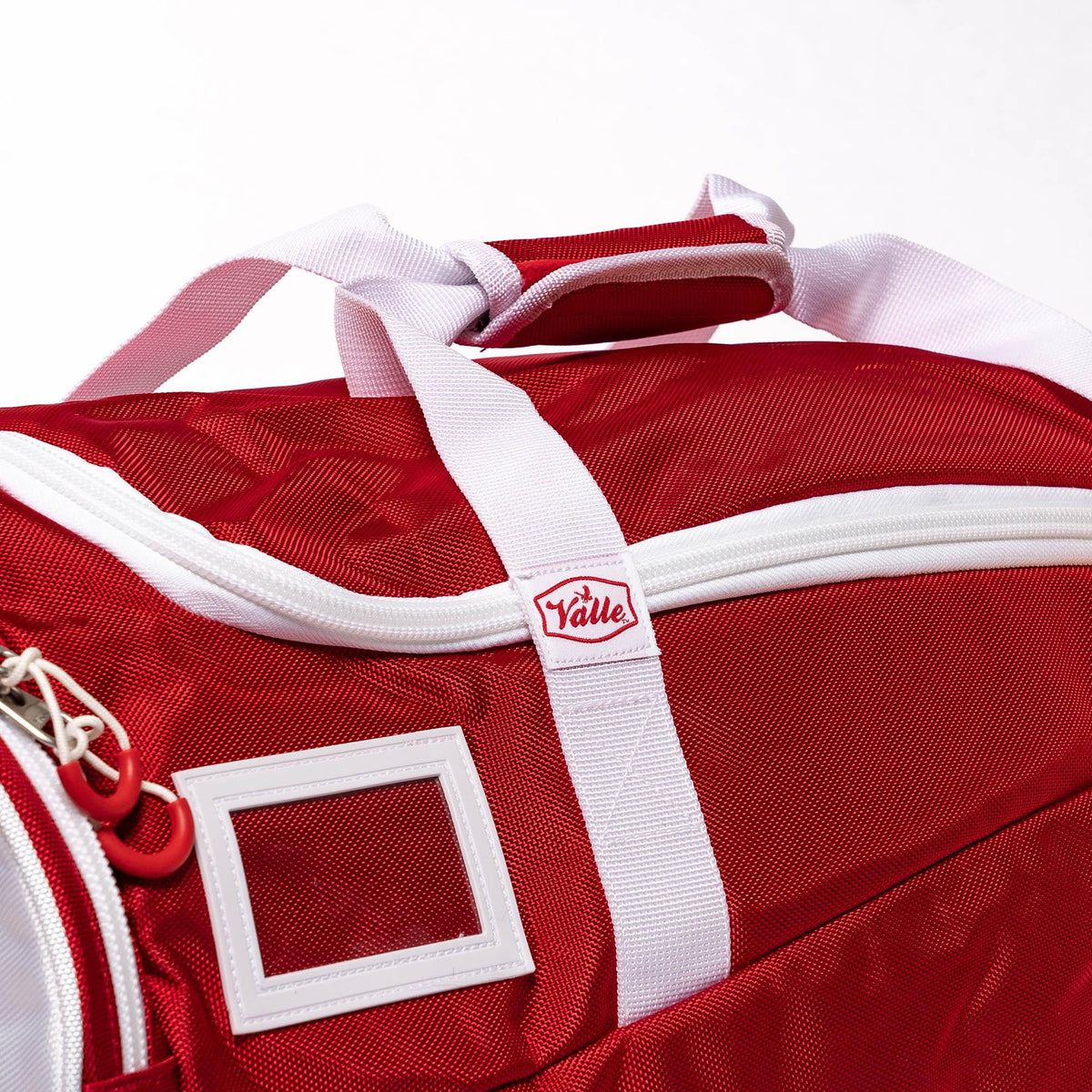 Top of the red Players Duffle showing the wrapped handles, Valle zipper tab and clear ID card window