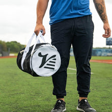 Player carrying the black Valle Eagle Youth Equipment Bag by its handles at the field, logo end cap out