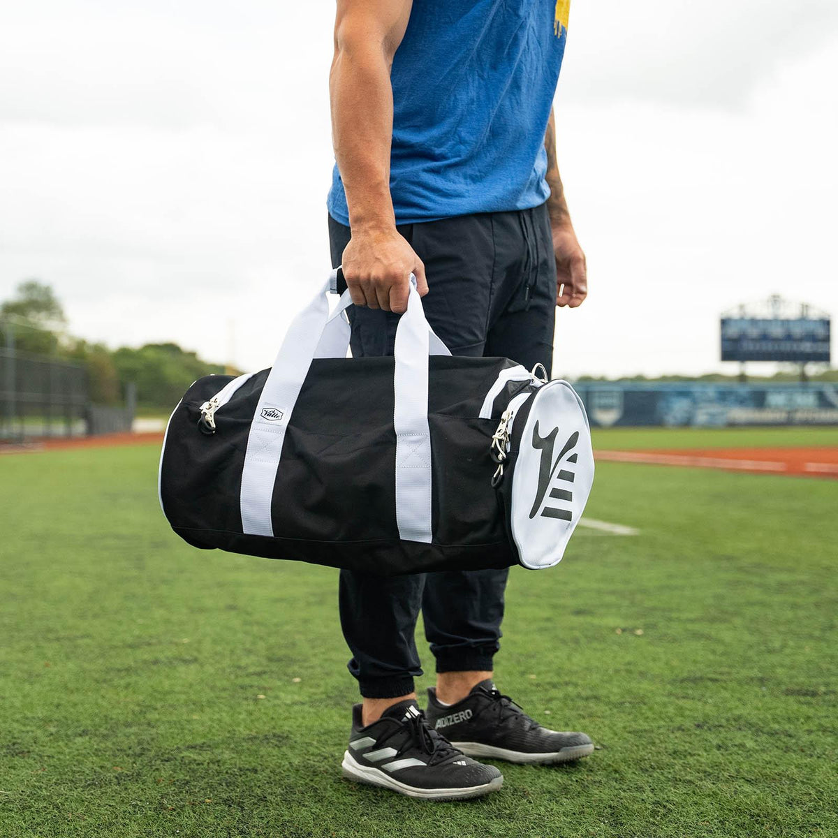 Young player holding the black Valle Eagle Youth Equipment Bag by the handles at an outdoor field