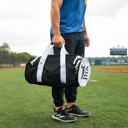 Young player holding the black Valle Eagle Youth Equipment Bag by the handles at an outdoor field