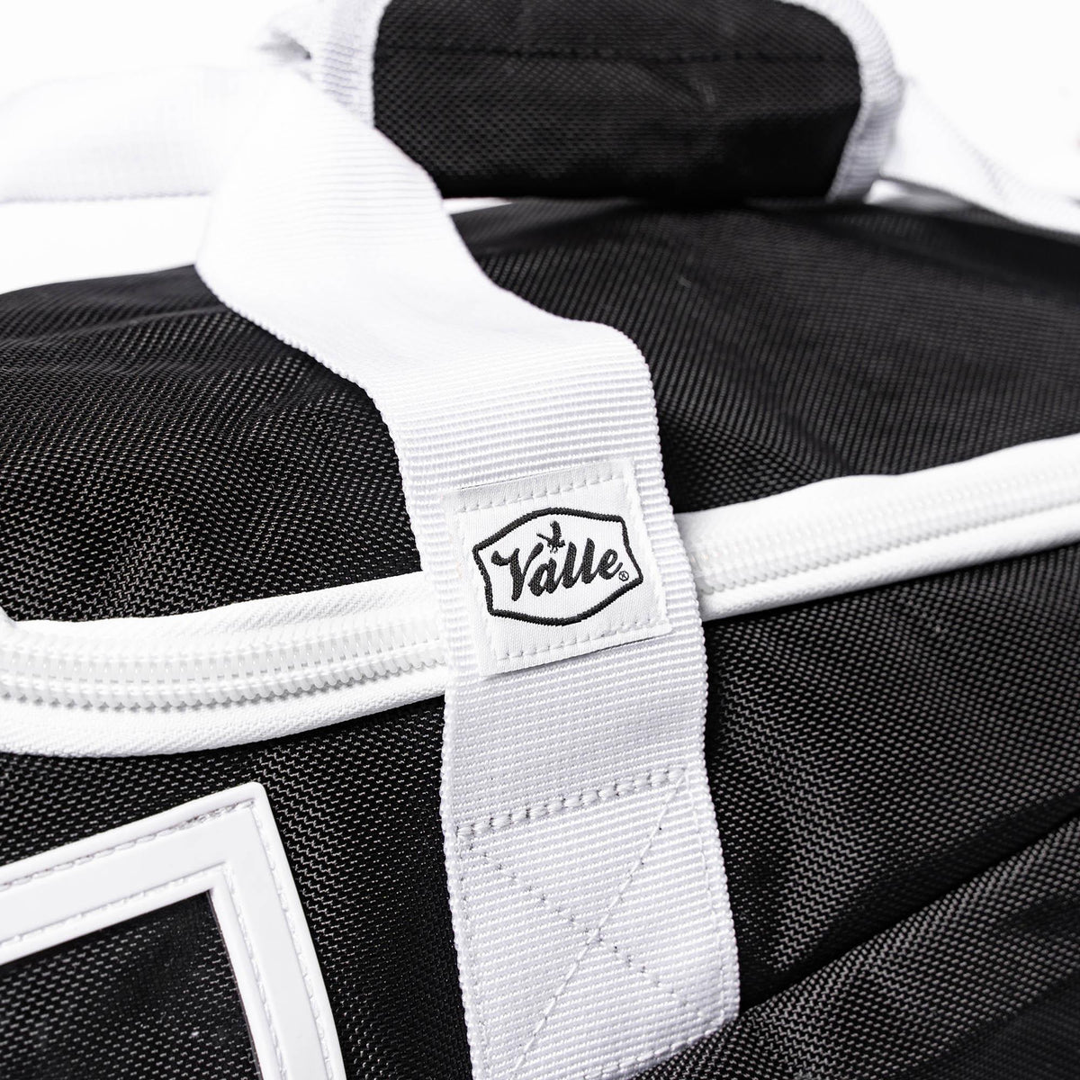 Stitched Valle tab where the white strap crosses the black fabric of the Youth Equipment Bag